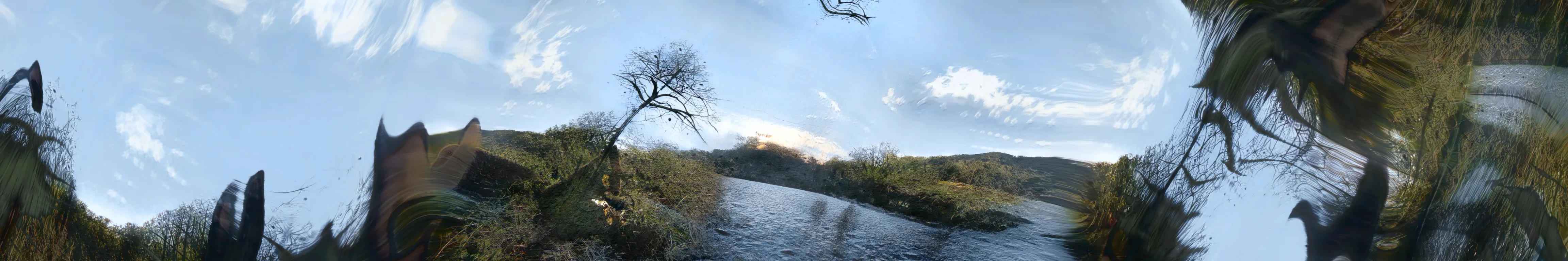 .full-width A still from ‘A short ride through hyperspace’ by Tim Murray-Browne. The AI-rendered image shows a lake under a blue sky turning into distorte echoes of this image towards its edges.