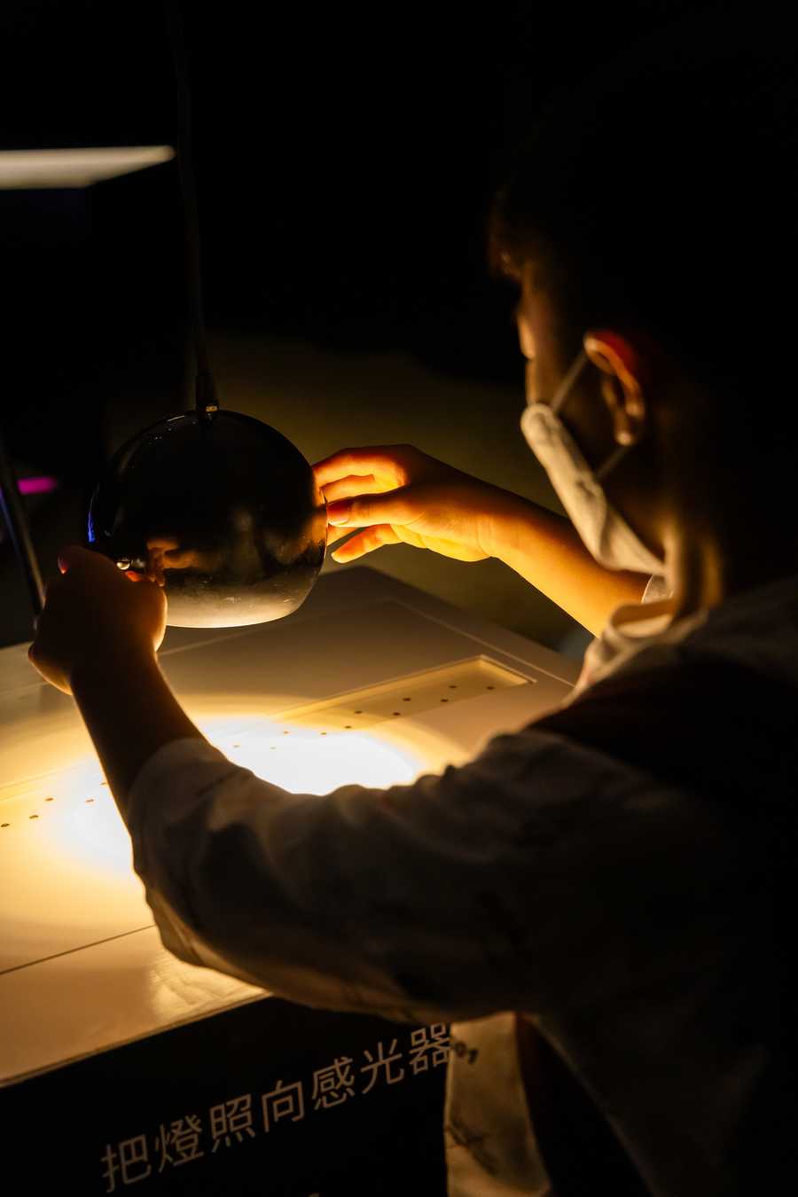 The interactive sound installation “Cave of Sounds” by Tim Murray-Browne and the Music Hackspace Ensemble, exhibited at Macao International Arts Festival. A boy directs a lamp onto an array of light sensors to control different harmonics of a fundamental. Photo: Instituto Cultural de Macau